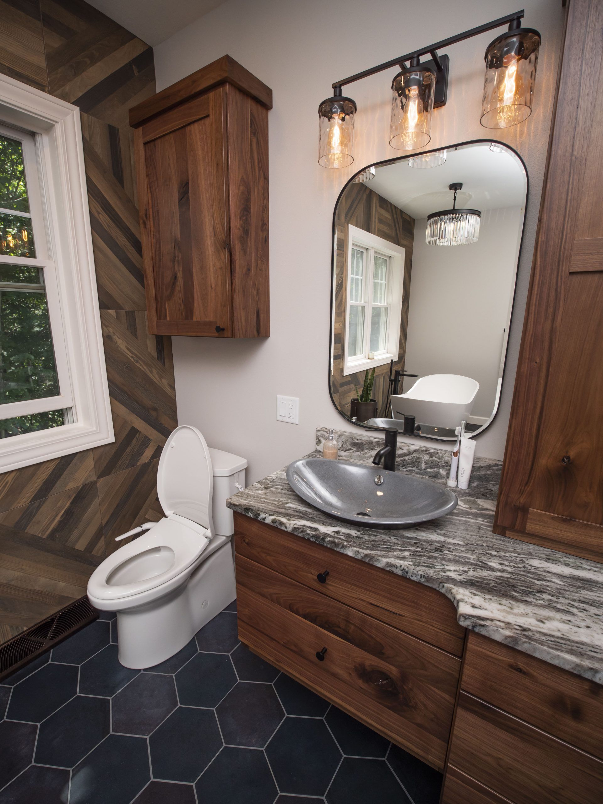 Bathroom with wood accents, geometric tile floor, and a unique vessel sink.