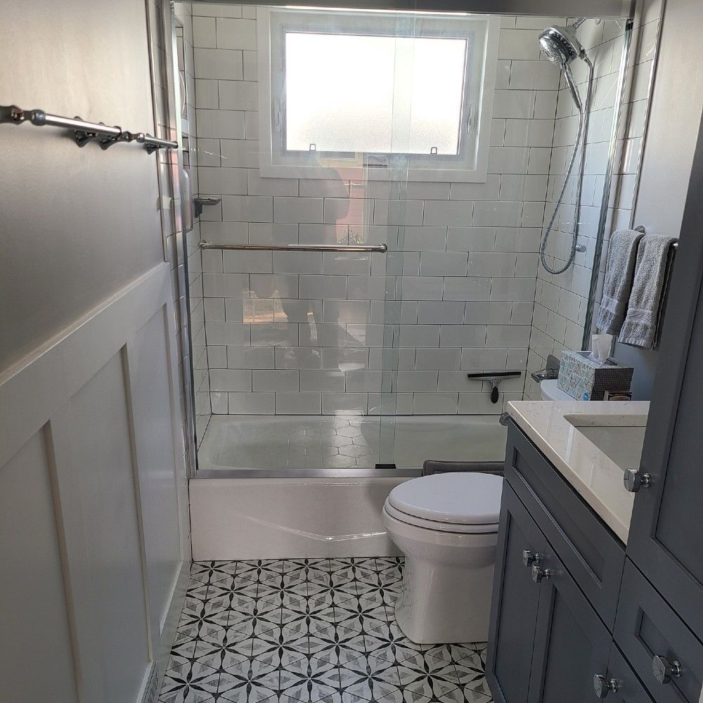 Small bathroom with patterned floor tiles, white subway tile shower, blue vanity.