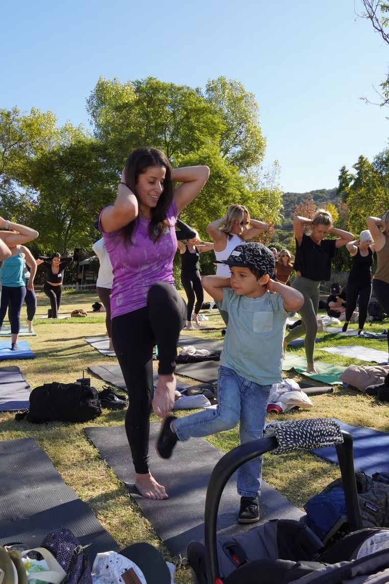 People doing a group exercise class outdoors on a grassy lawn in the sun
