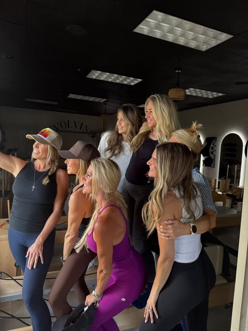 Group of people posing in a fitness studio with mirrors and ceiling lights