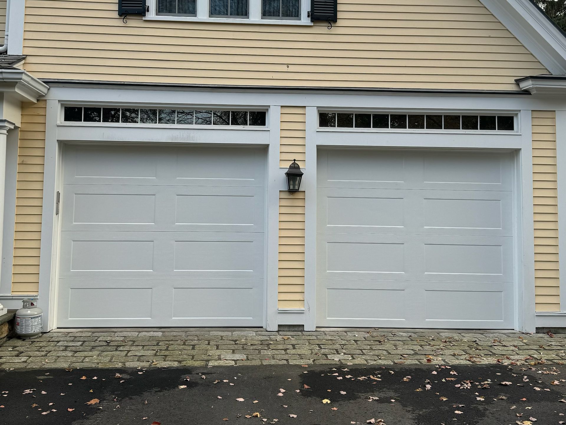 A yellow house with two white garage doors