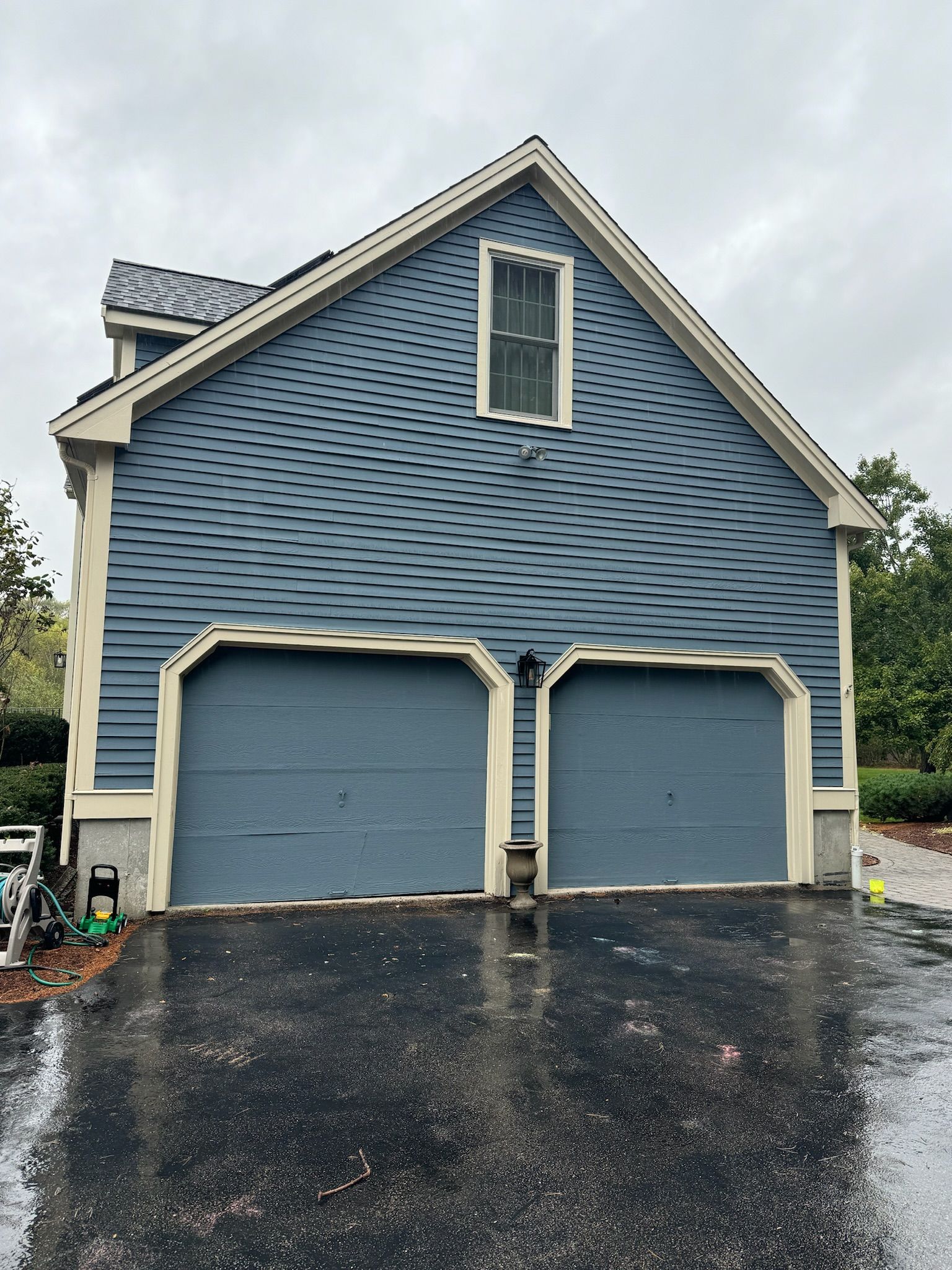 A blue garage with two garage doors and a window