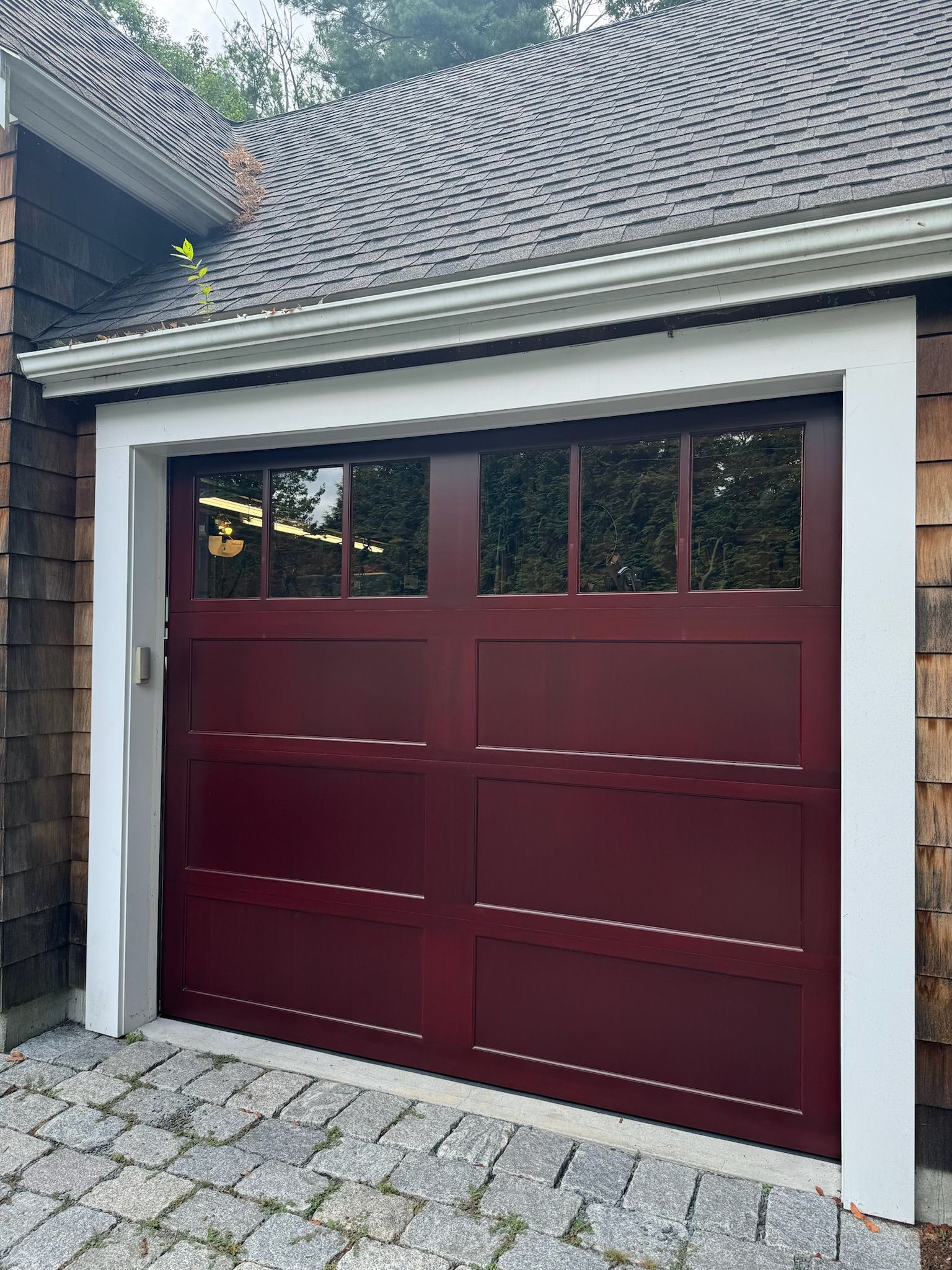 A red garage door is on the side of a house.