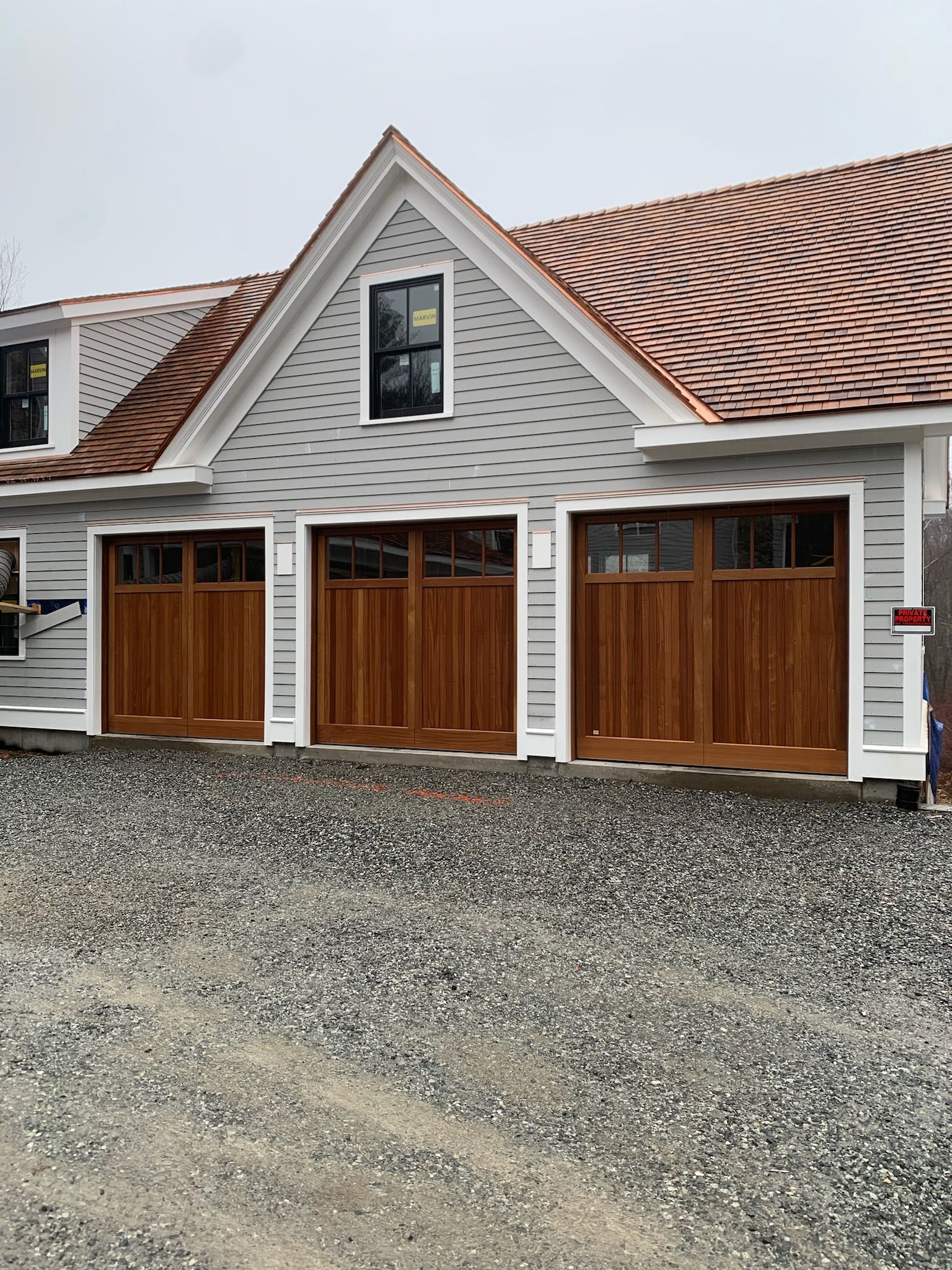 A house with three wooden garage doors and a copper roof.