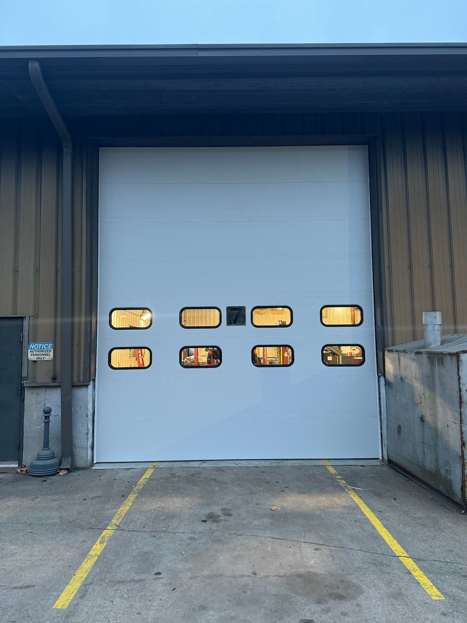 A white garage door with a lot of windows is sitting in front of a building.