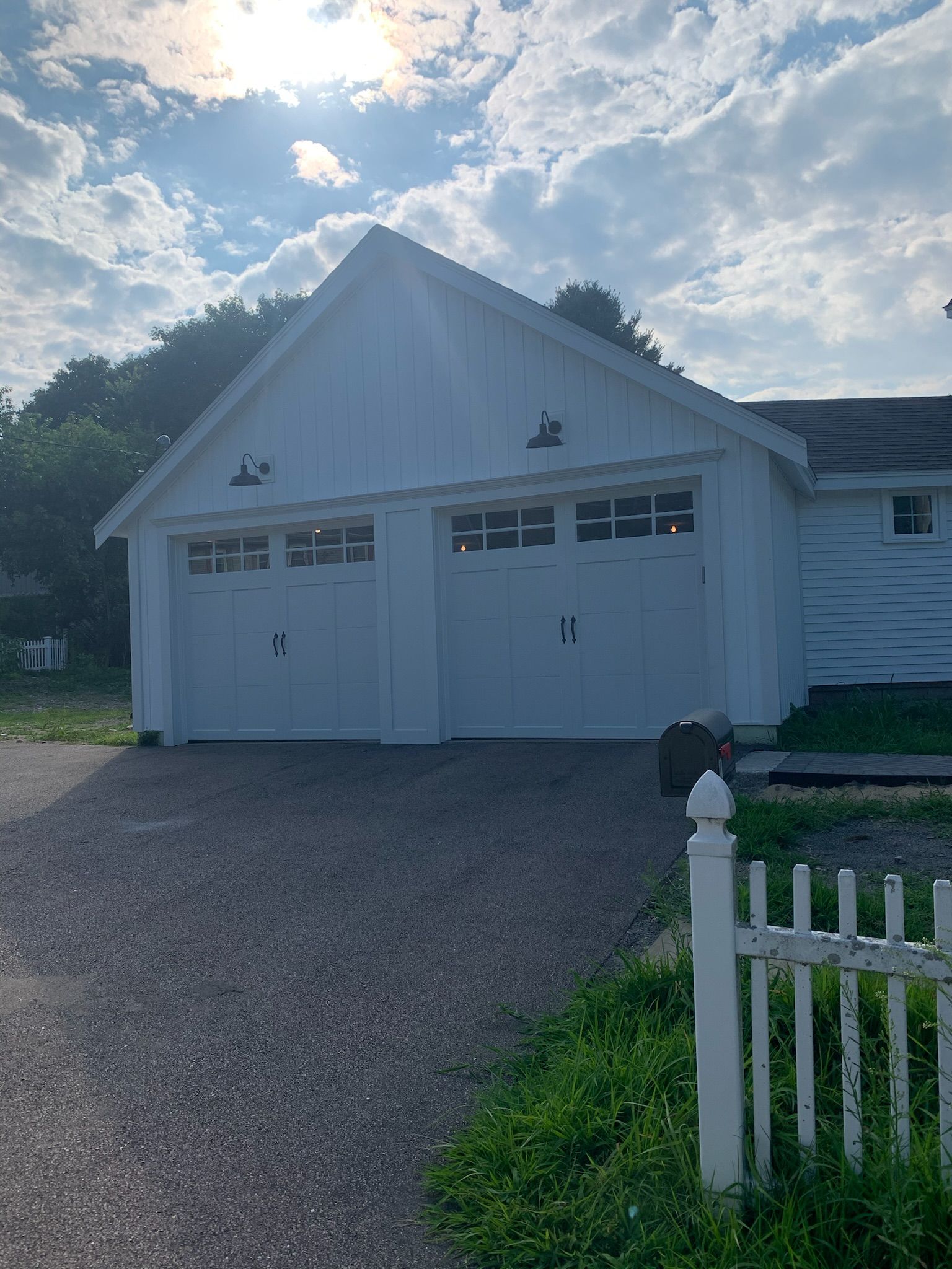 A white garage with a white picket fence in front of it
