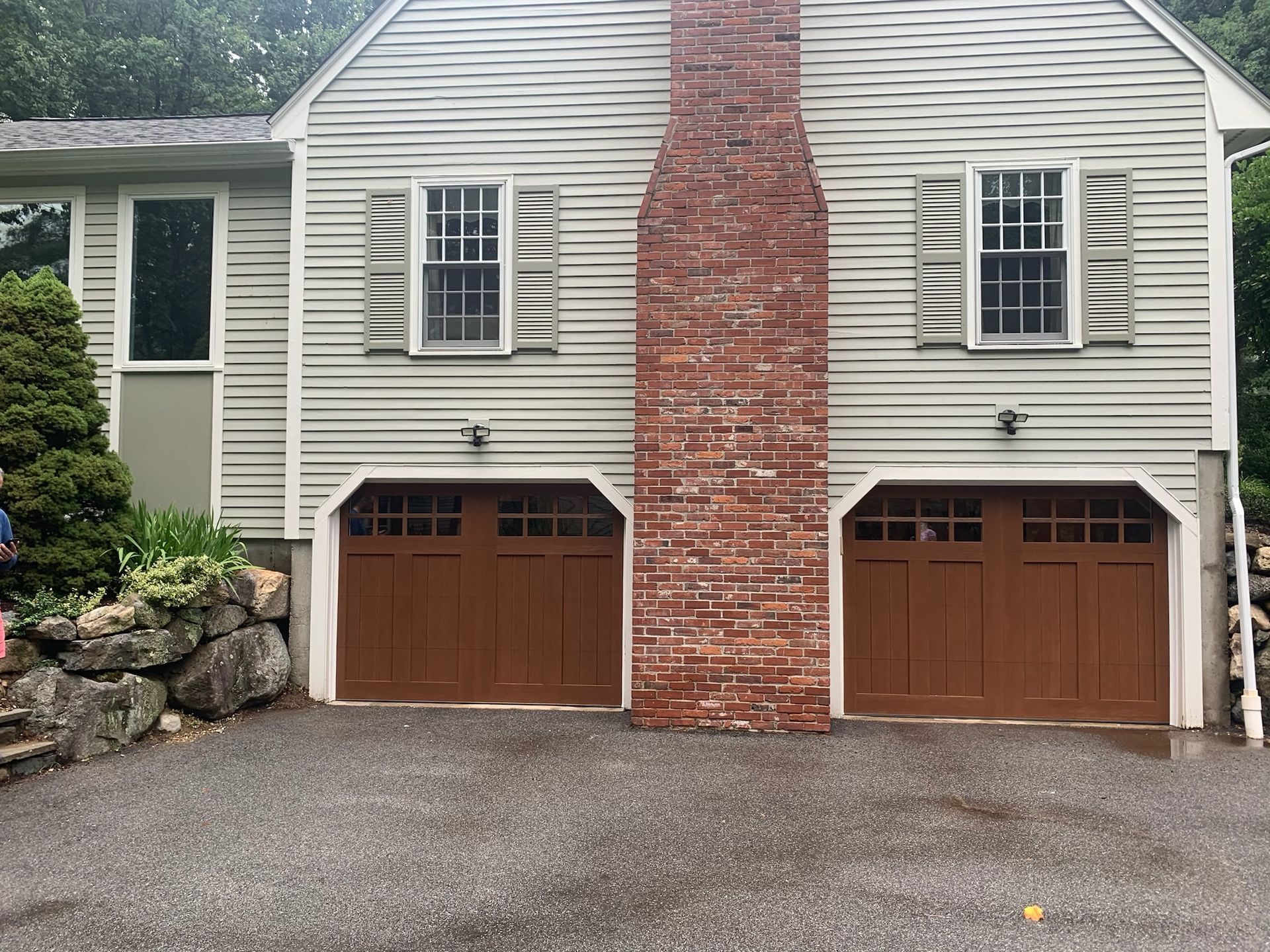 A house with two garage doors and a brick chimney