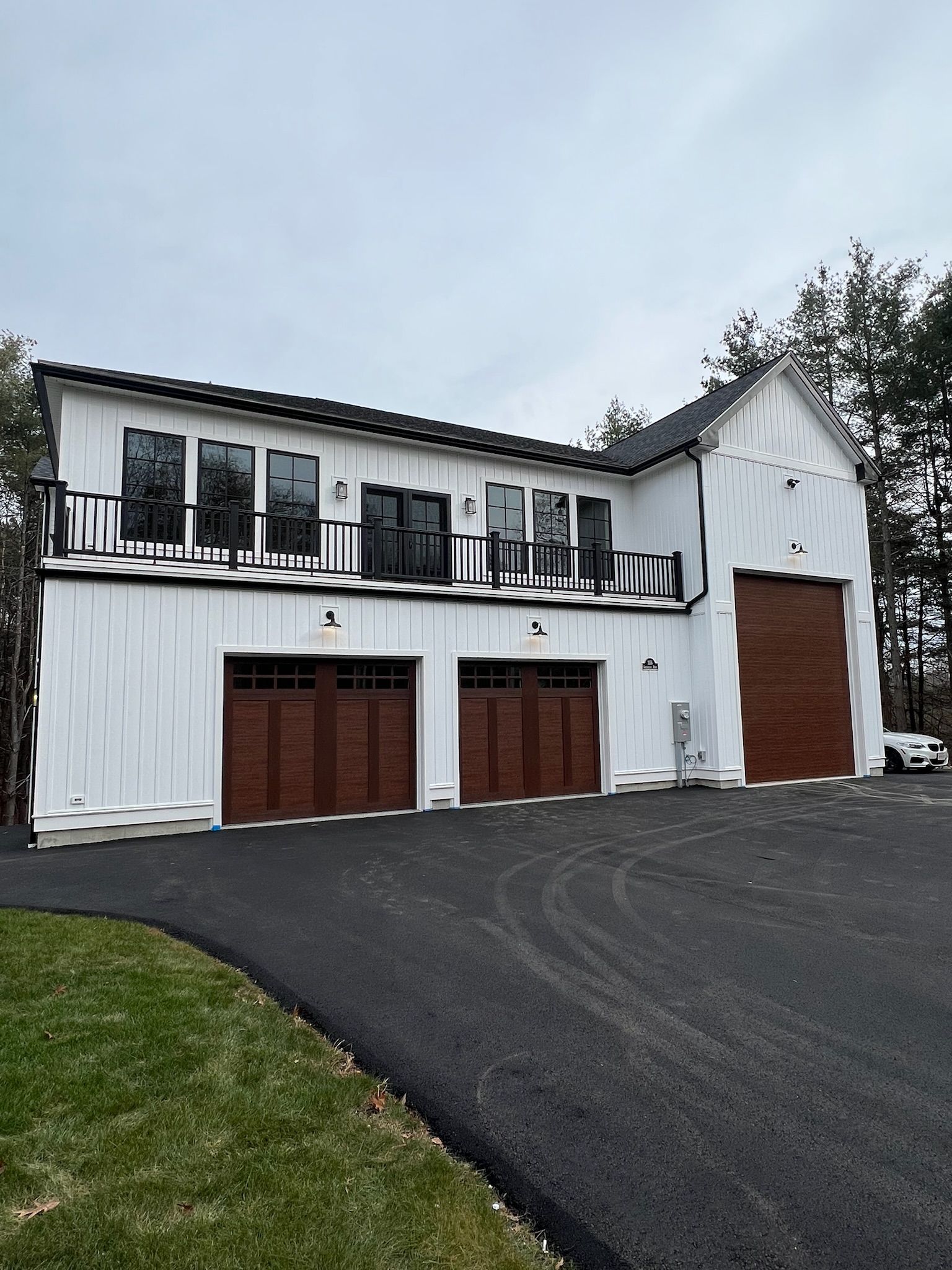 A white house with three garage doors and a car parked in front of it.