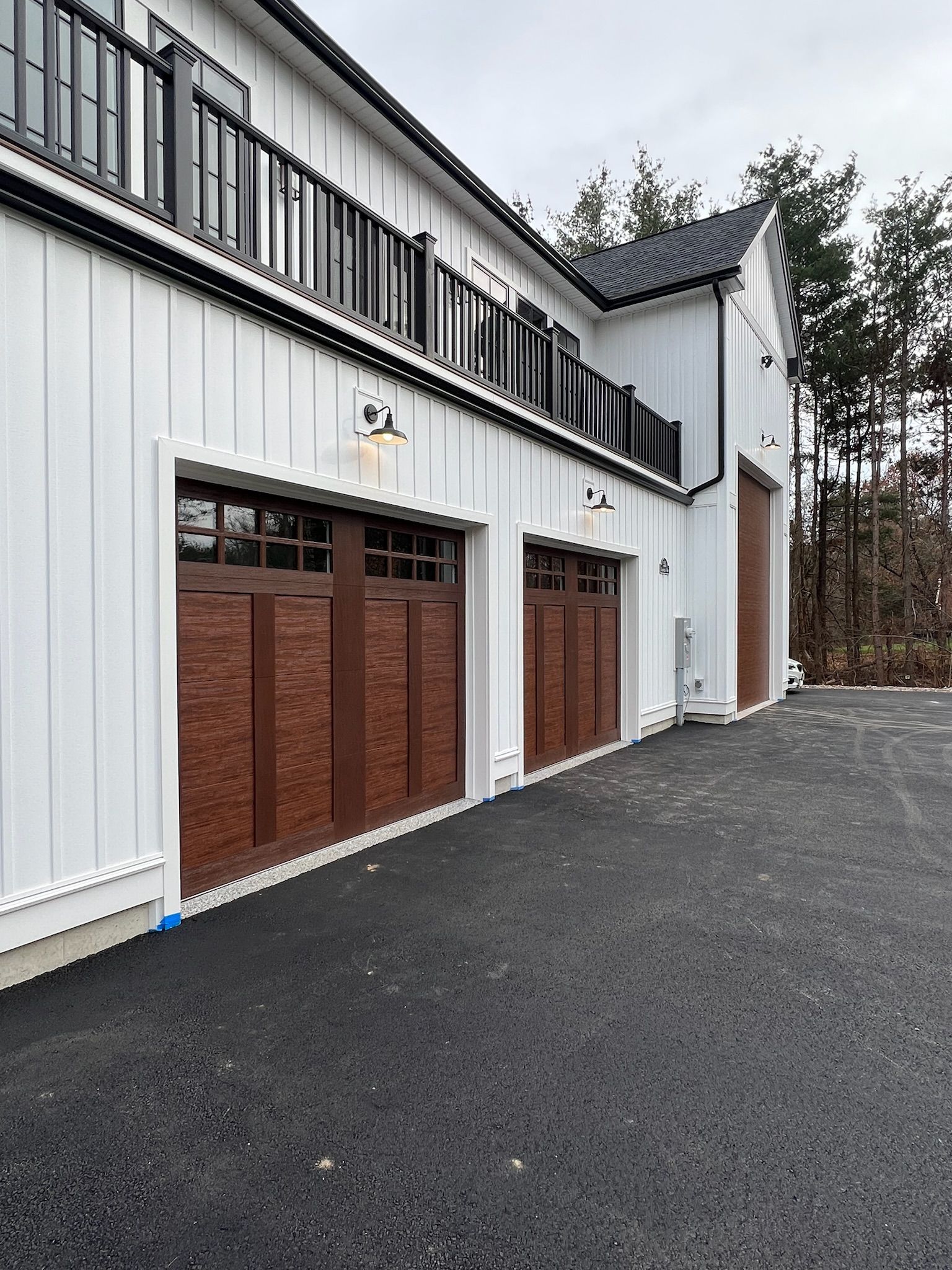 A white house with three garage doors and a black driveway.