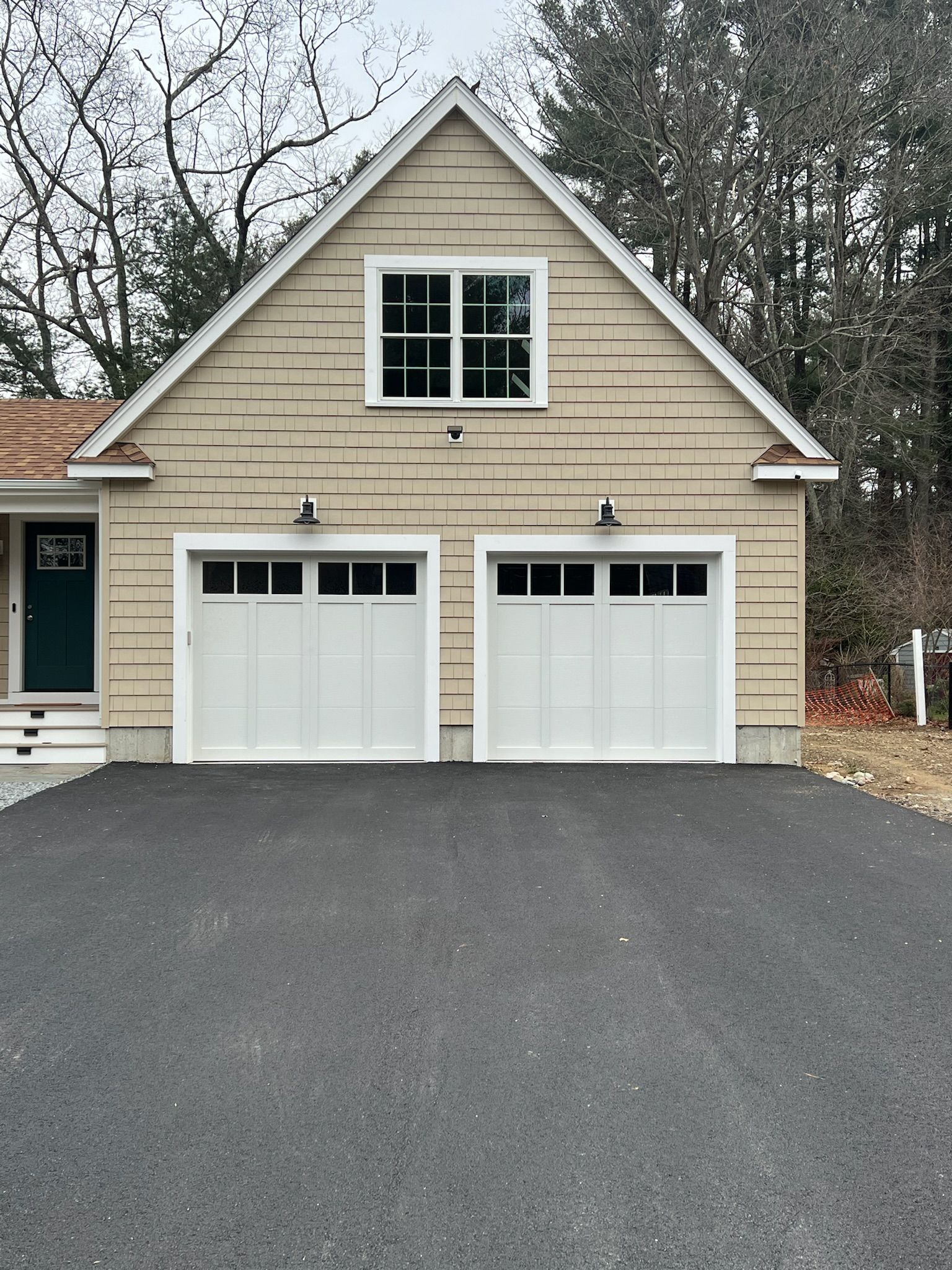 A house with two garage doors and a driveway in front of it.