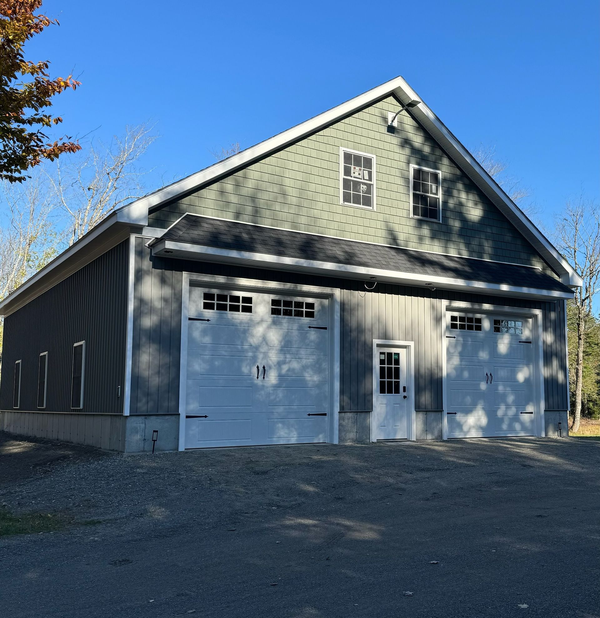 A garage with a green siding and white garage doors