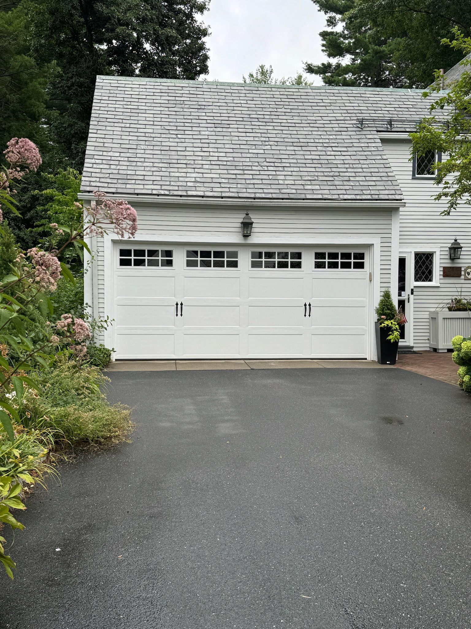 A white garage door is sitting in front of a white house.