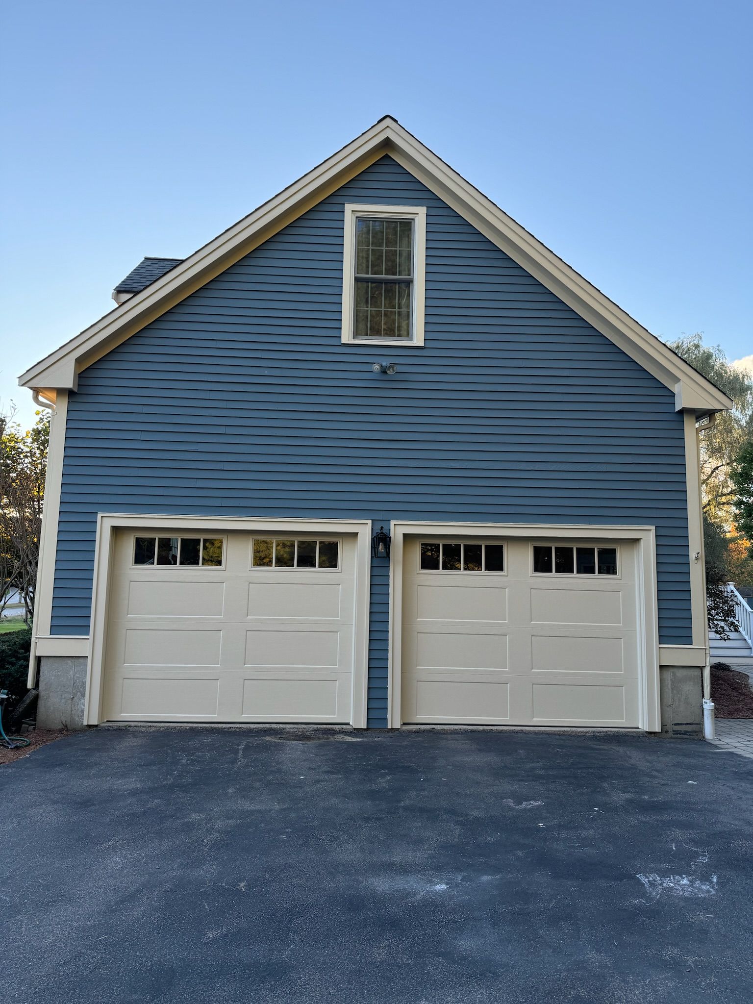A blue house with two white garage doors and a window
