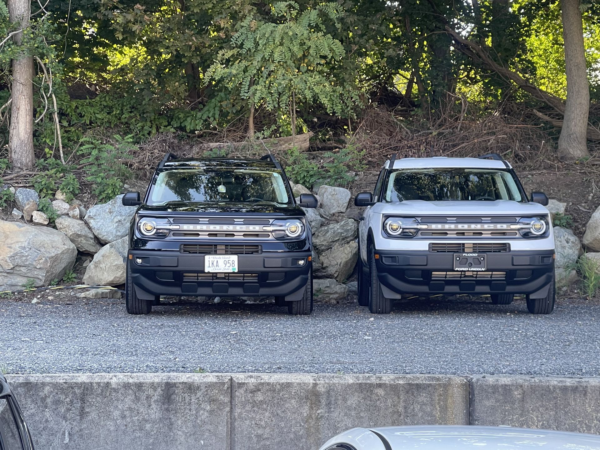 Two ford bronco sport suvs are parked next to each other on a gravel road.