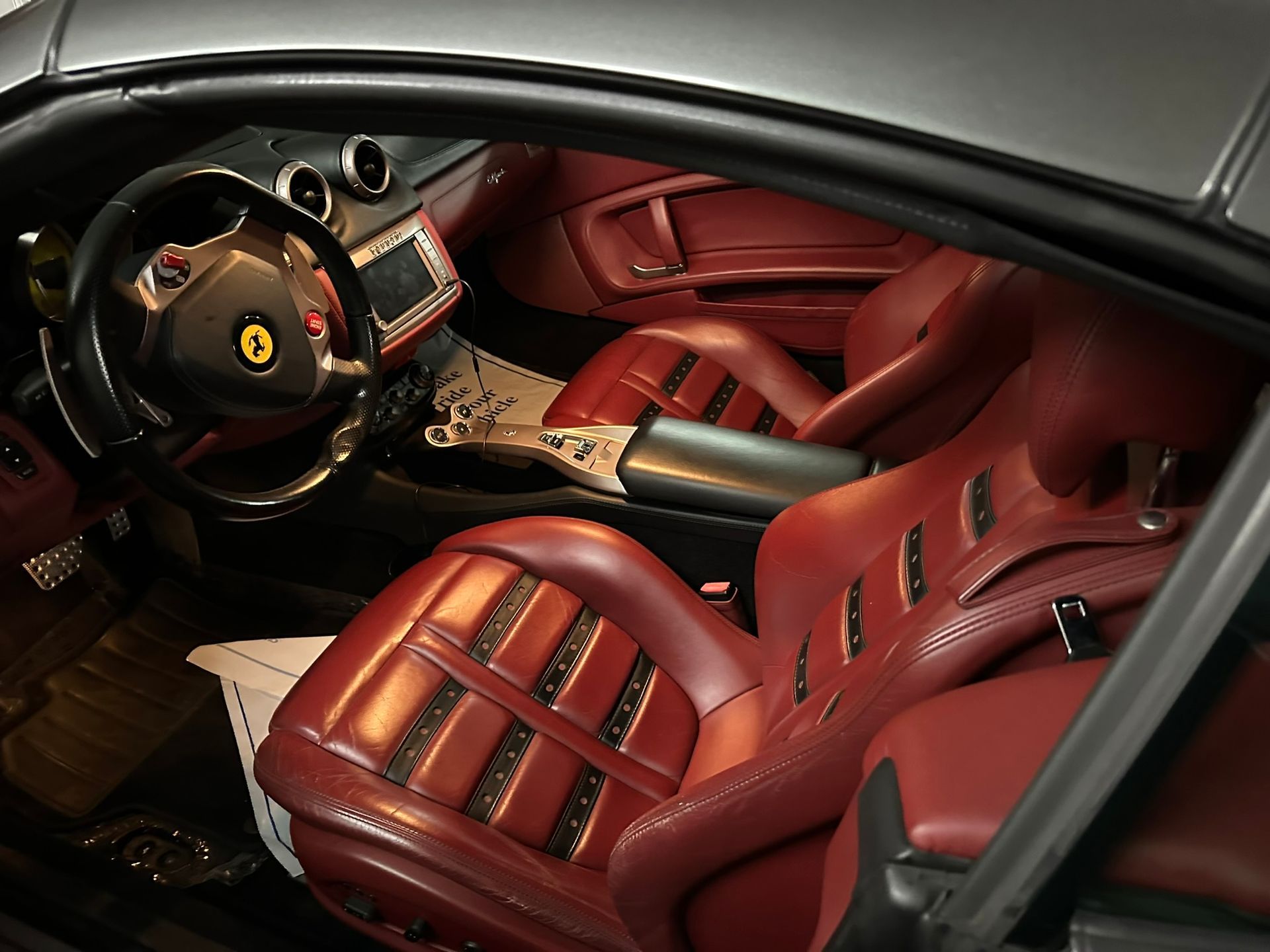 The interior of a car with red seats and a steering wheel.