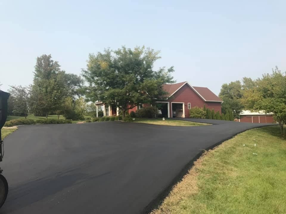 A red house with a black driveway in front of it.