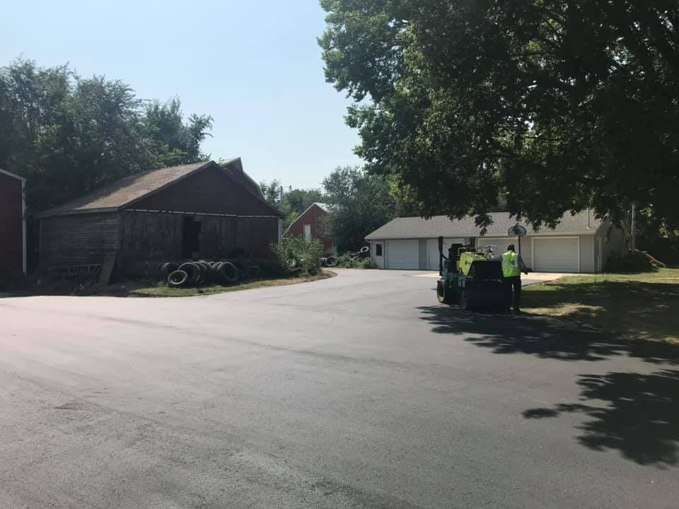 A man in a yellow vest is standing on the side of a road in front of a house.