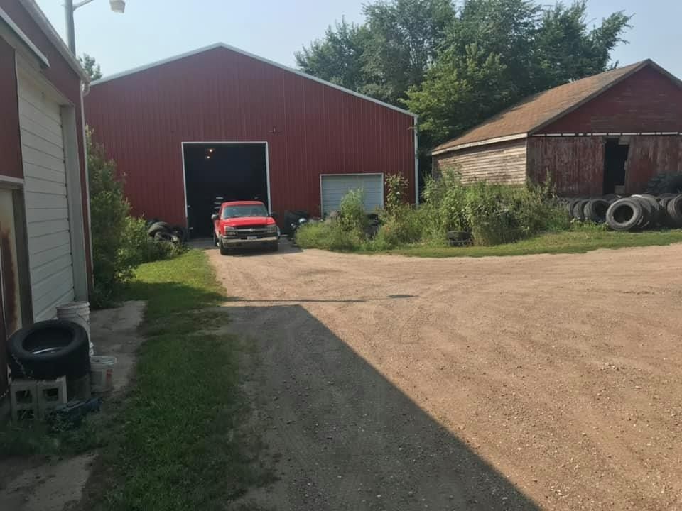 A red truck is parked in front of a red barn.