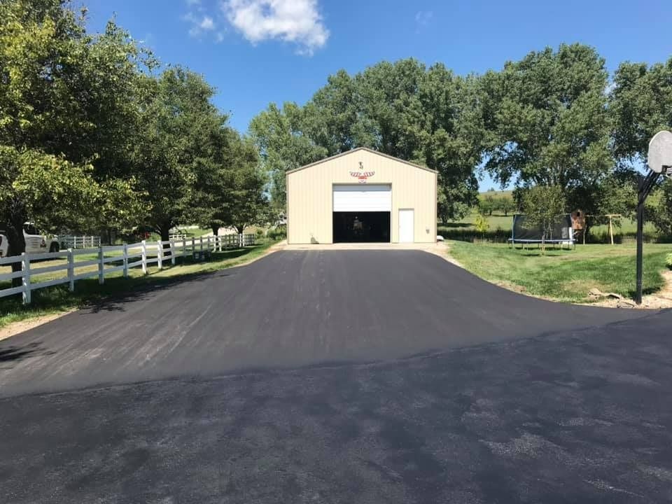 A garage with a basketball hoop in front of it and a driveway leading to it.