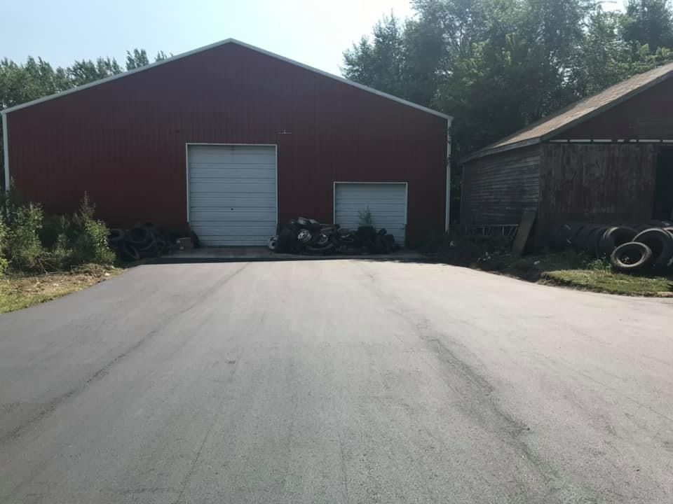 A red barn with a white garage door is sitting next to a road.