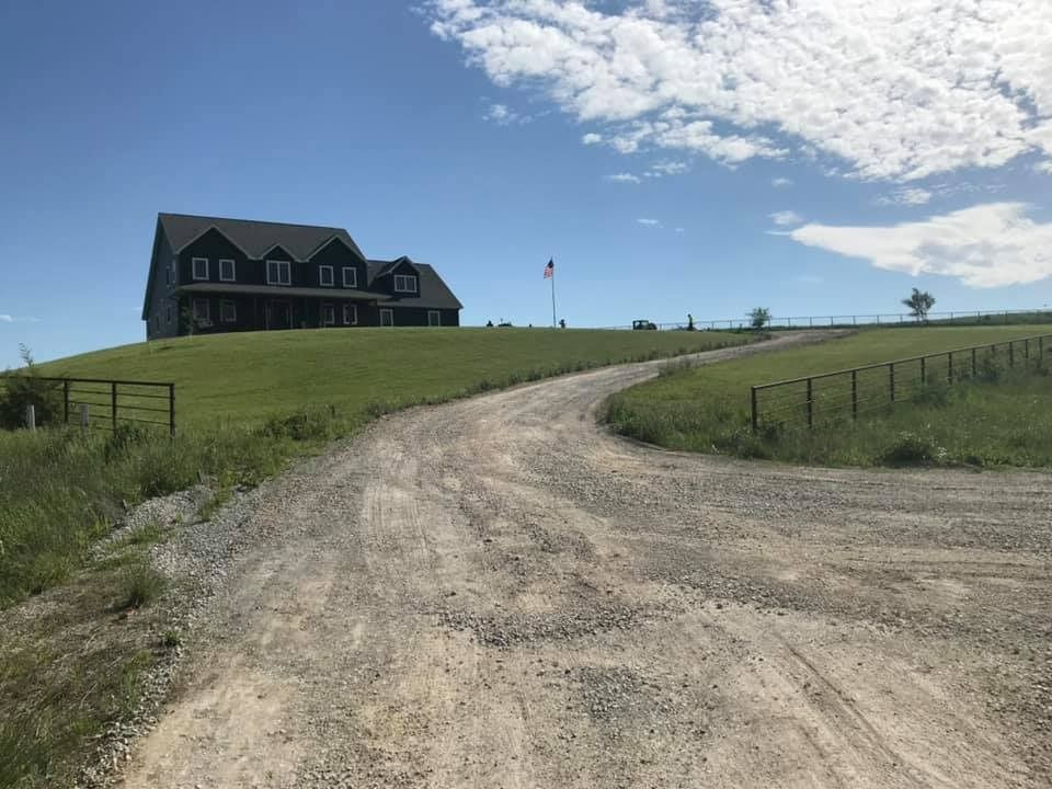 A dirt road leading to a house on top of a hill