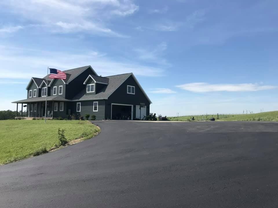 A large black house with a large driveway leading to it.