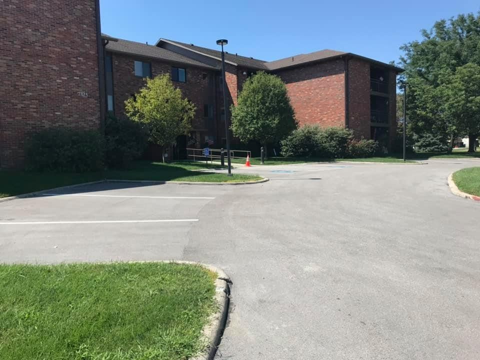 A brick apartment building with a parking lot in front of it.