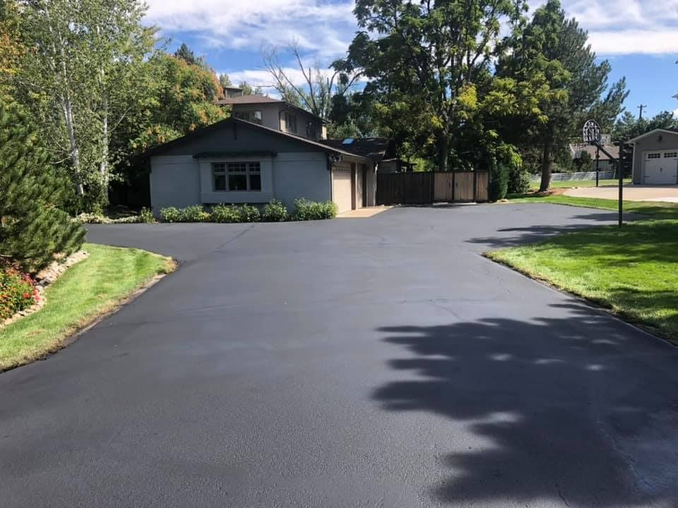 A driveway leading to a house with a basketball hoop in the background.