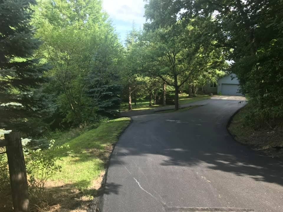 A road with trees on both sides of it and a garage in the background.