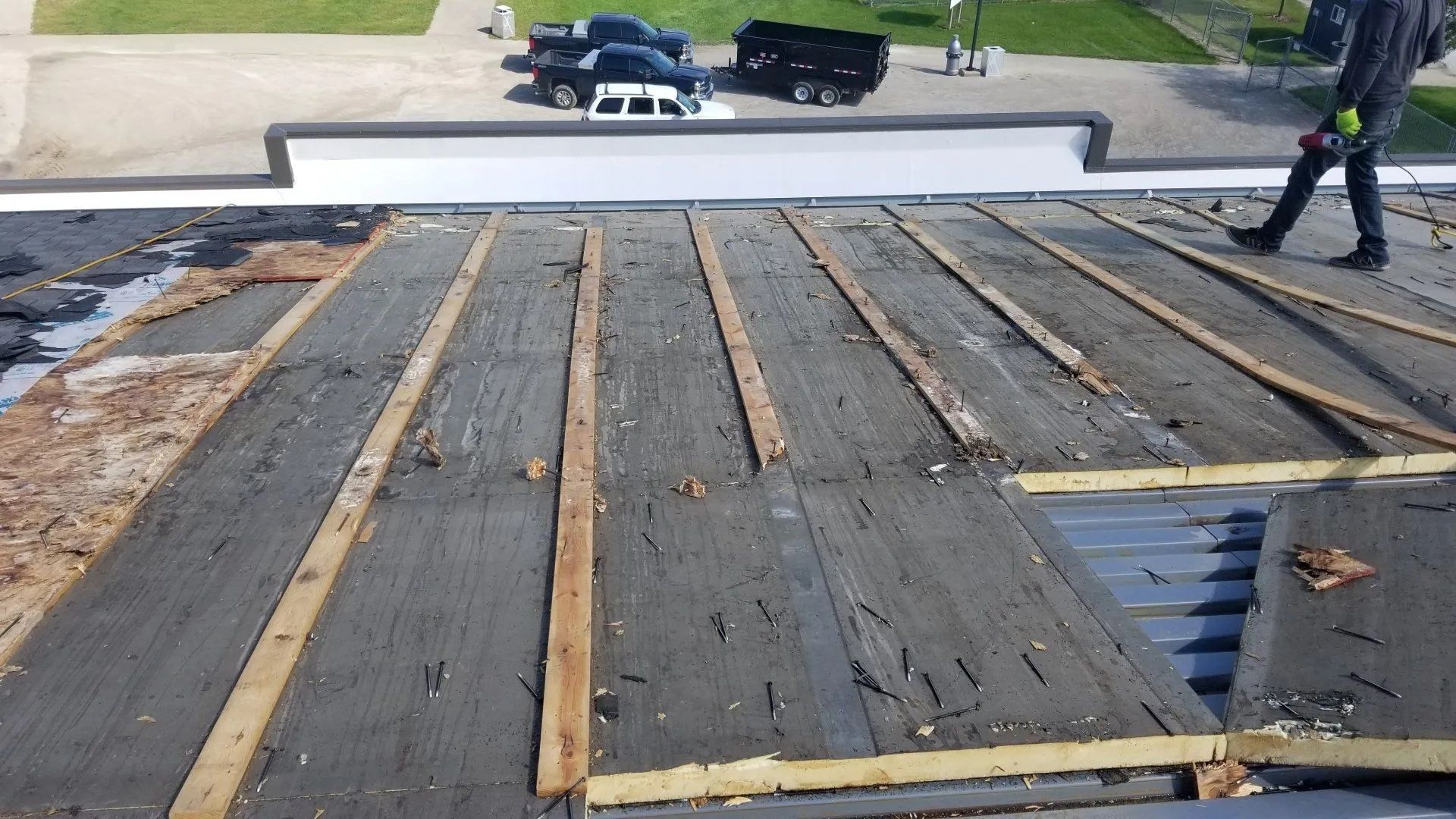 Damaged rooftop with exposed wooden framing and workers inspecting repairs.