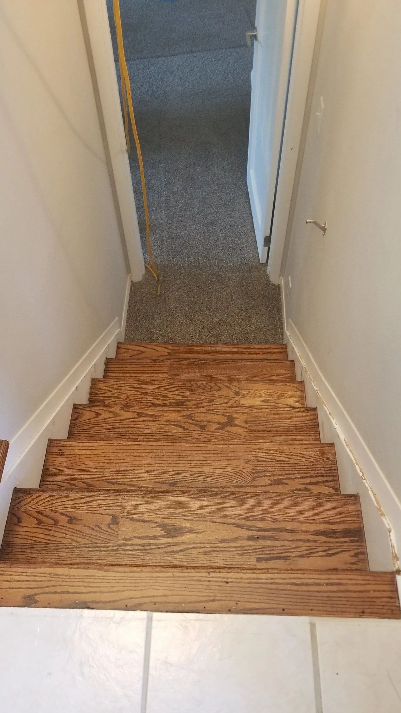 Wooden staircase with carpeted upper landing and white walls, viewed from the top looking down
