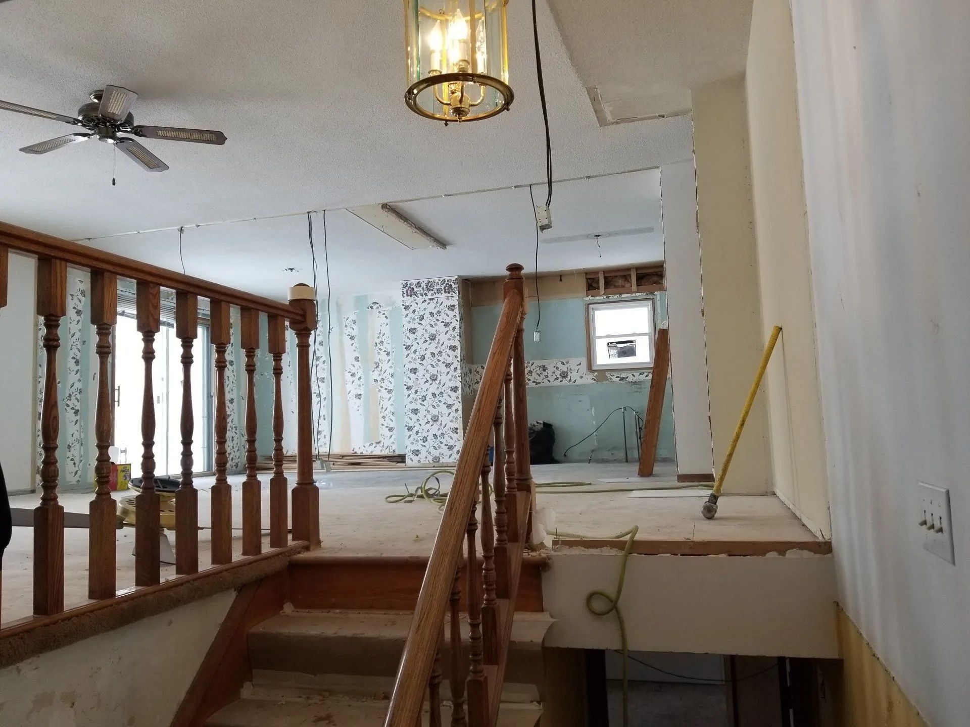Interior of a house under renovation, with stairs, exposed ceiling, and construction tools.