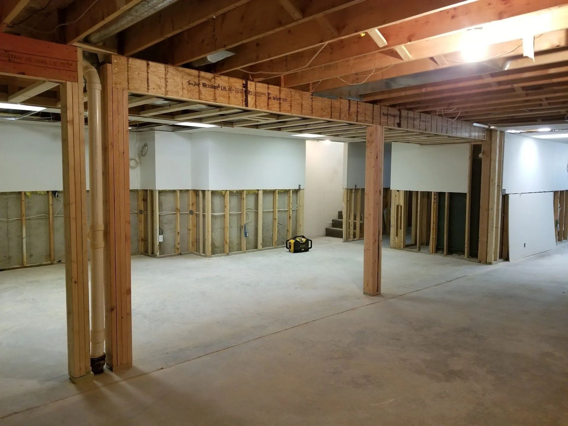 Unfinished basement interior with exposed beams, framing, and concrete floor