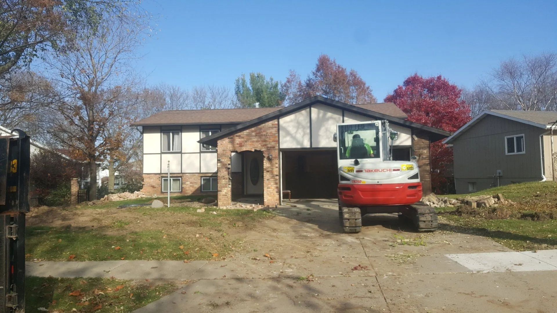 Single-story house with a red-and-white utility truck parked in the driveway, autumn trees in front.
