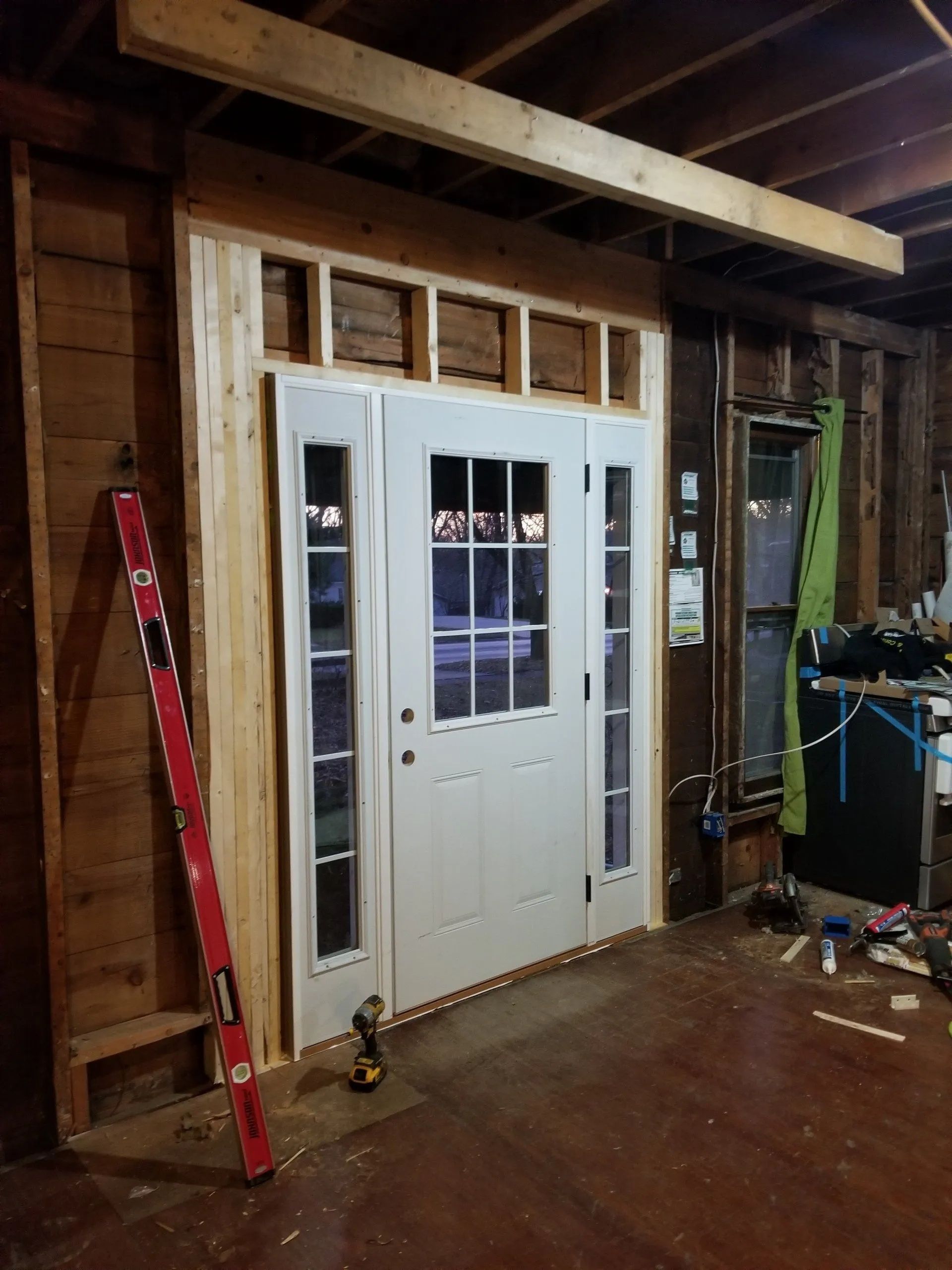 Partially finished room with a white double door framed by exposed wood and construction tools nearby