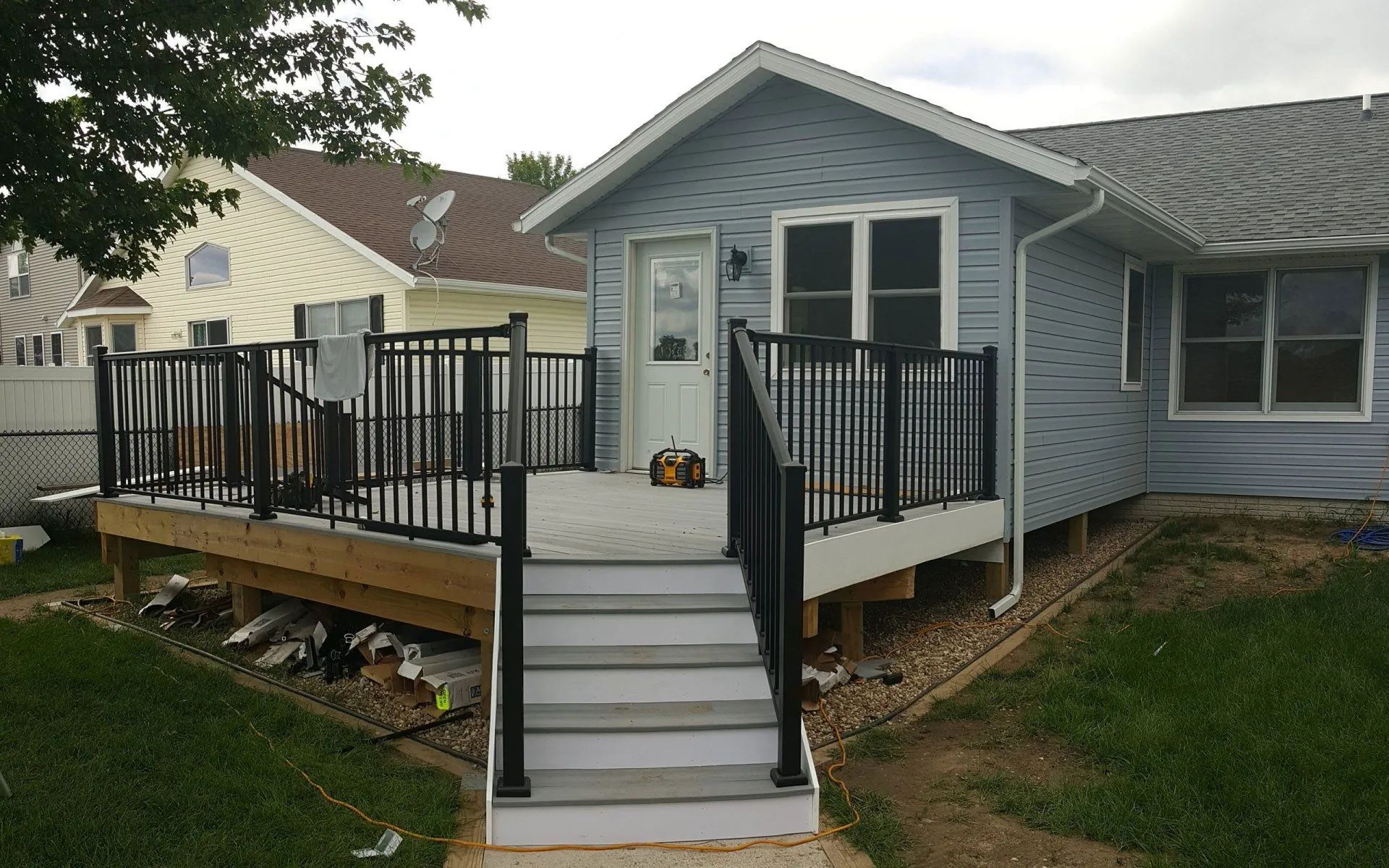Back deck with black railings and central steps leading to a blue-gray house.