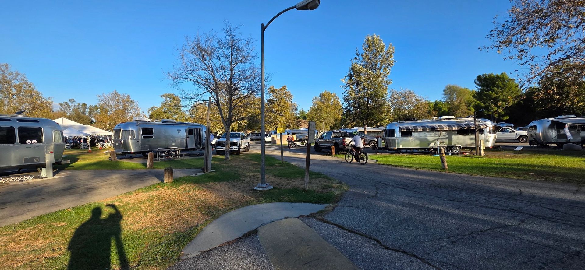 Shiny travel trailers parked at a campsite on a sunny day.