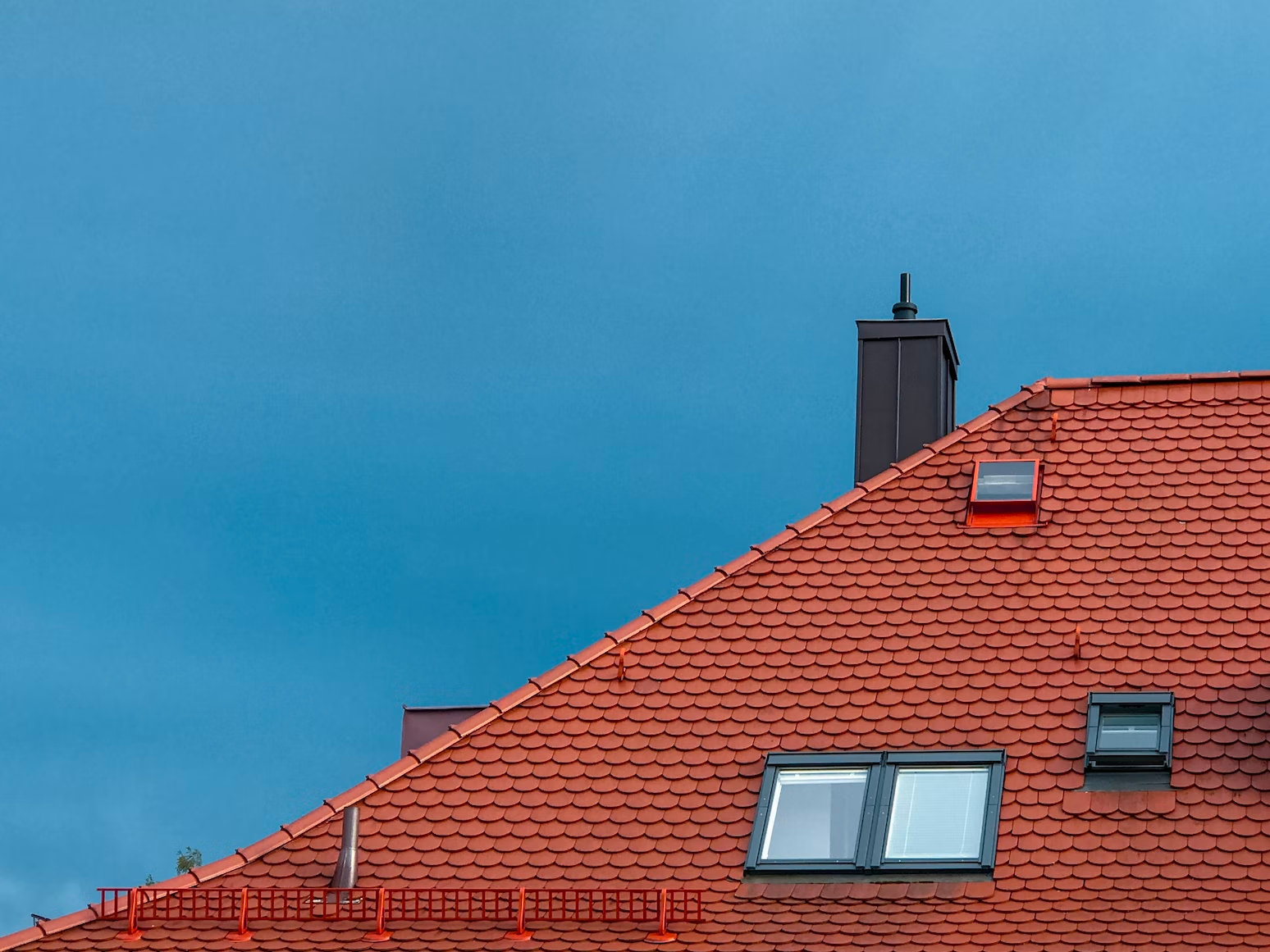 A roof with bright red clay shingles and skylights.