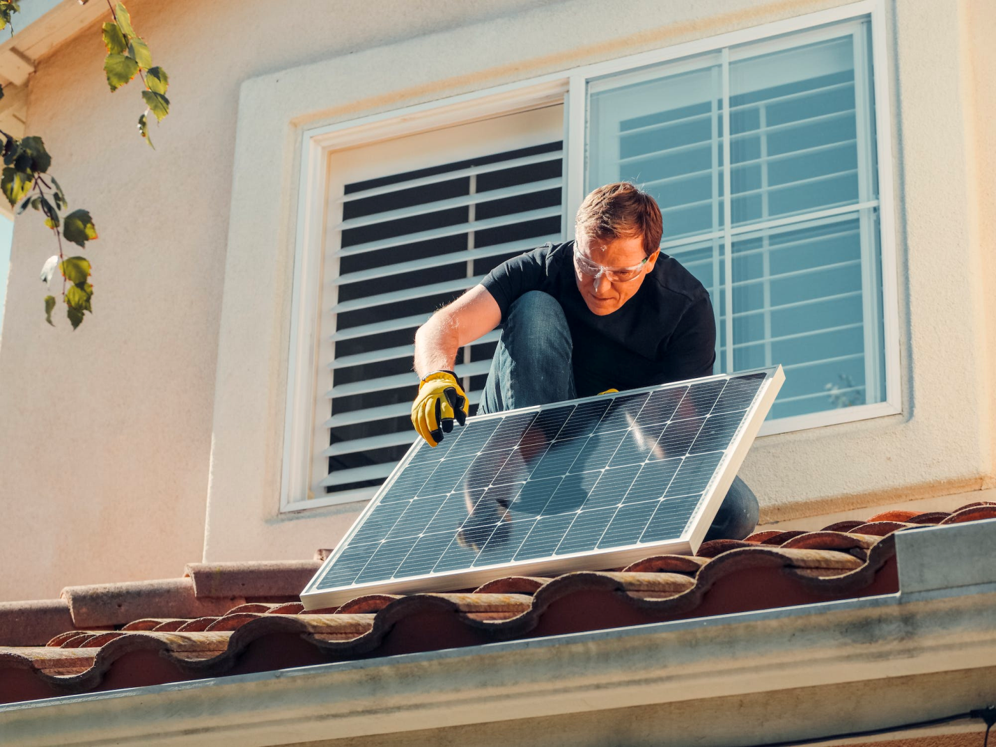 A homeowner cleans their solar panel while up on the roof.
