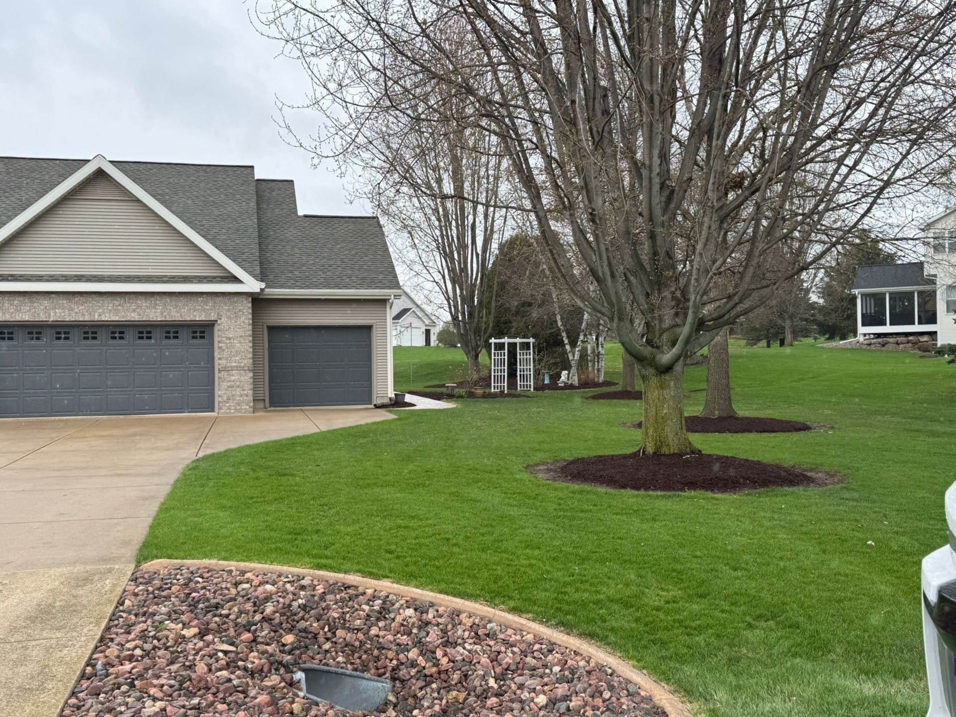 A house with two garages and a lush green lawn in front of it.
