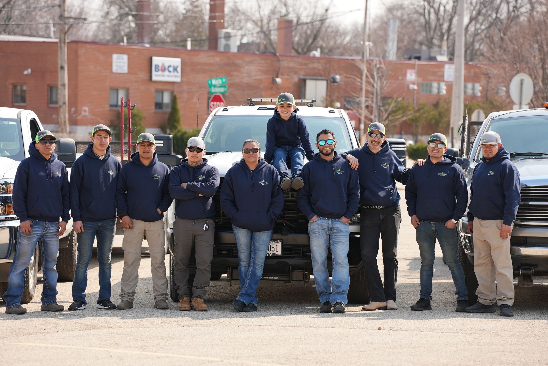 A group of men are posing for a picture in front of trucks