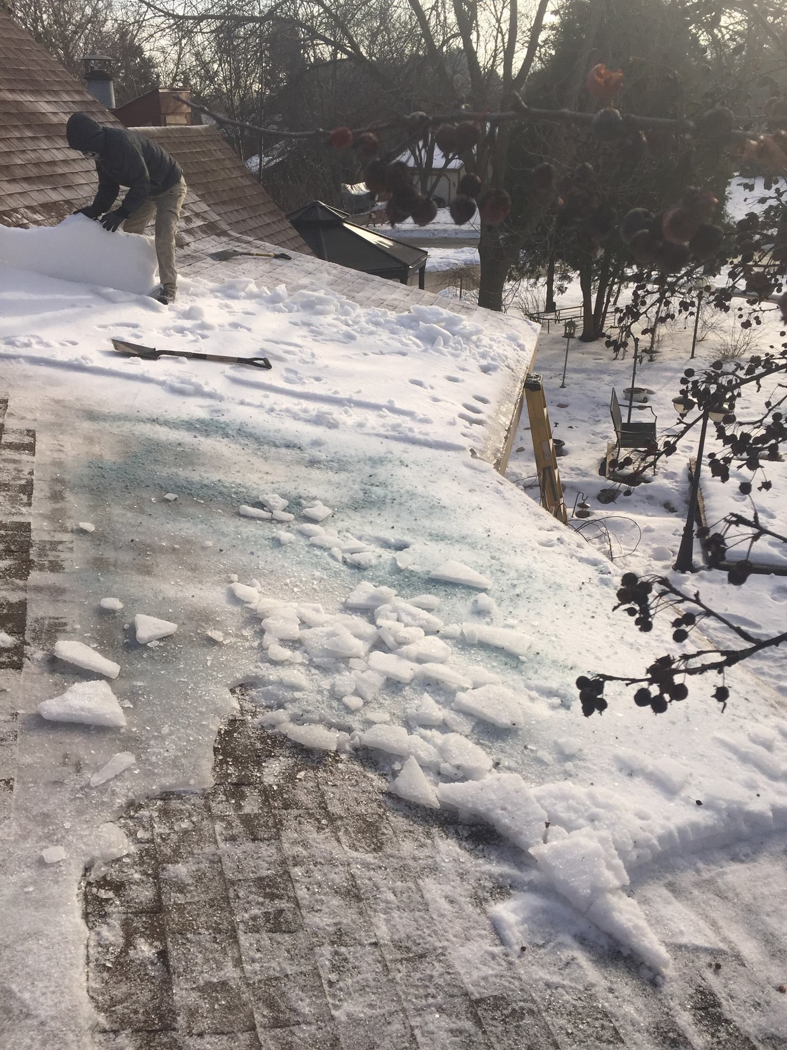 A person is shoveling snow from the roof of a building.