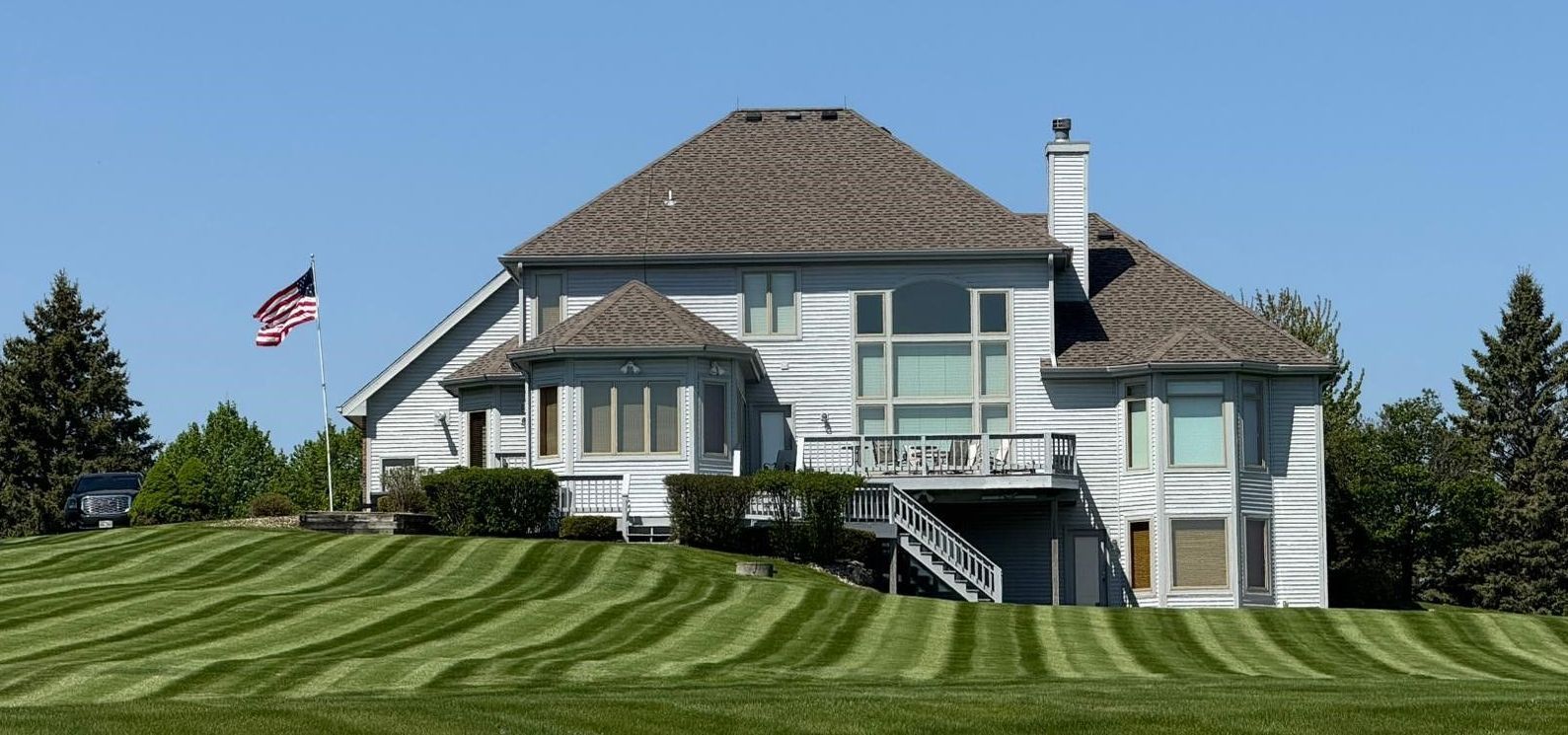 A large house is sitting on top of a lush green hill.