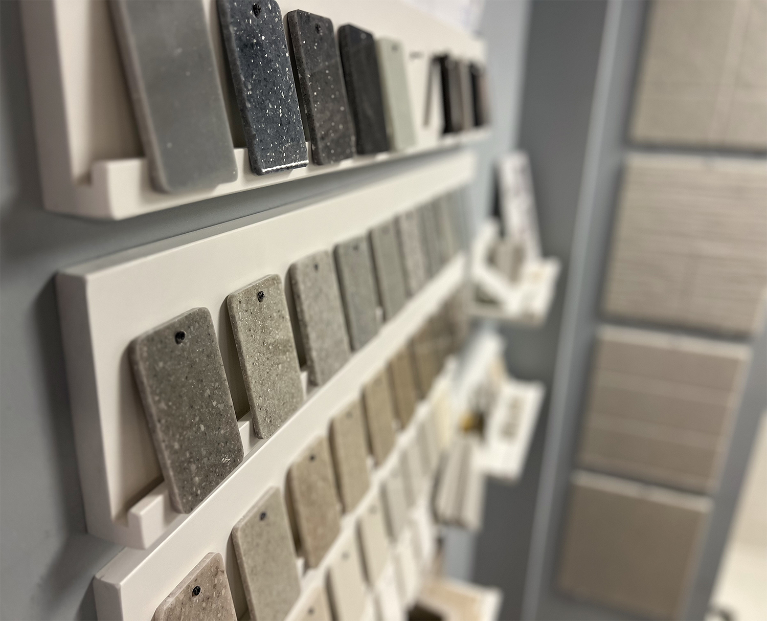 Close-up of countertop samples in varying colors displayed on white shelves in a showroom.