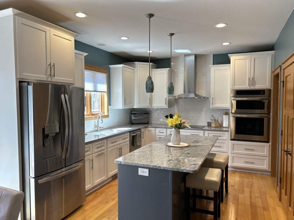 A kitchen with white cabinets and stainless steel appliances and a large island.