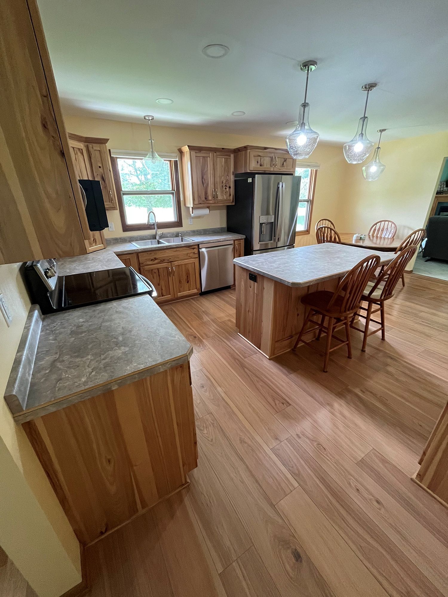 A kitchen with wooden cabinets, countertops, and flooring. A stainless steel refrigerator and dishwasher are present.