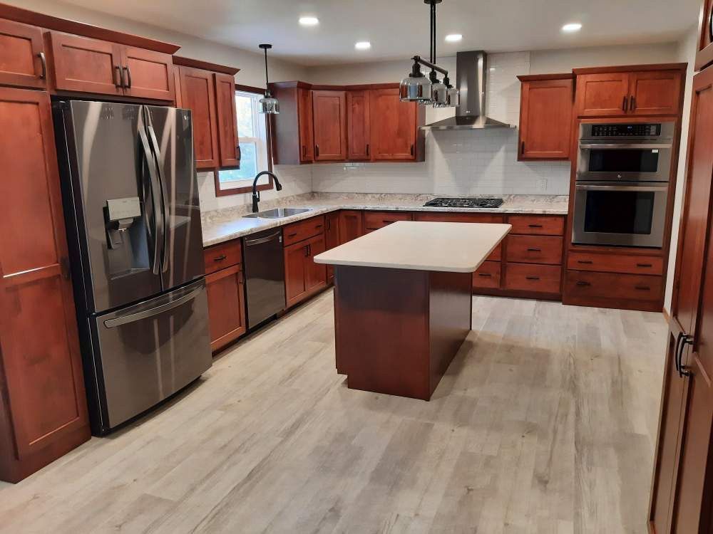 A newly renovated kitchen with cherry-stained cabinets, stainless steel appliances, and a center island with a light-colored countertop.