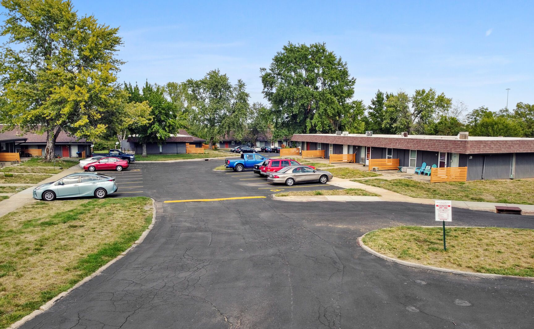 An elevated view of a residential complex with dark-roofed buildings, a paved parking area, and a red fire hydrant.