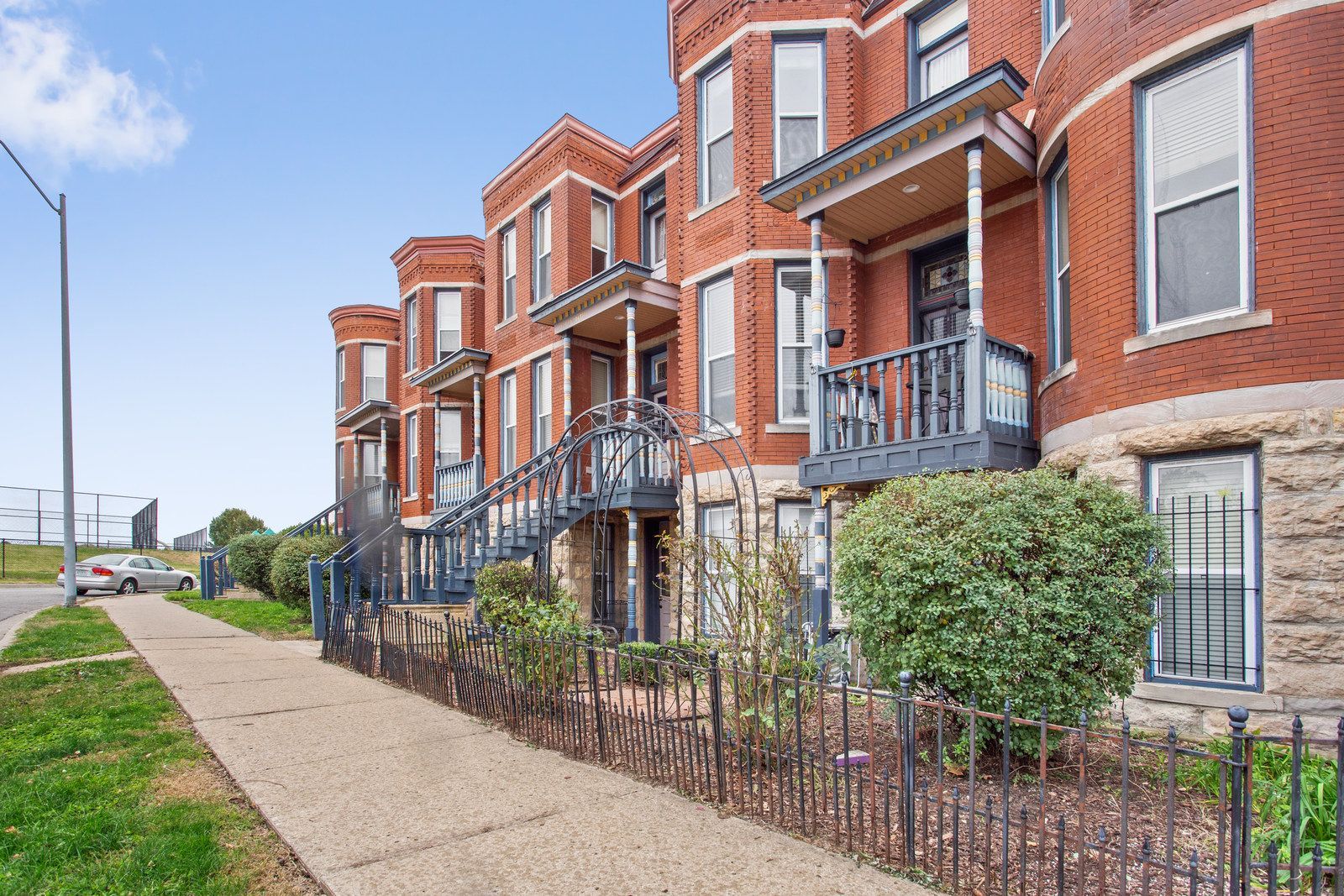 A two-story apartment building with beige siding and dark balconies, surrounded by dormant trees and landscaping.