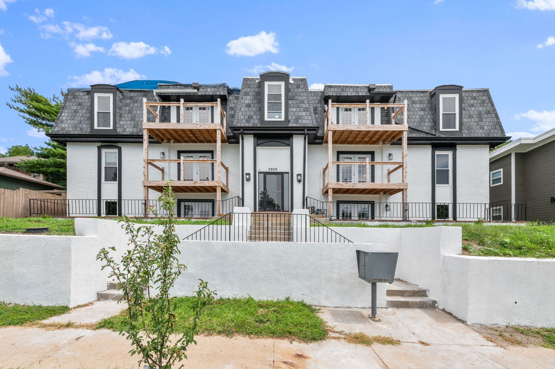 Two-story apartment building with light blue siding, white trim, and small wooden balconies.